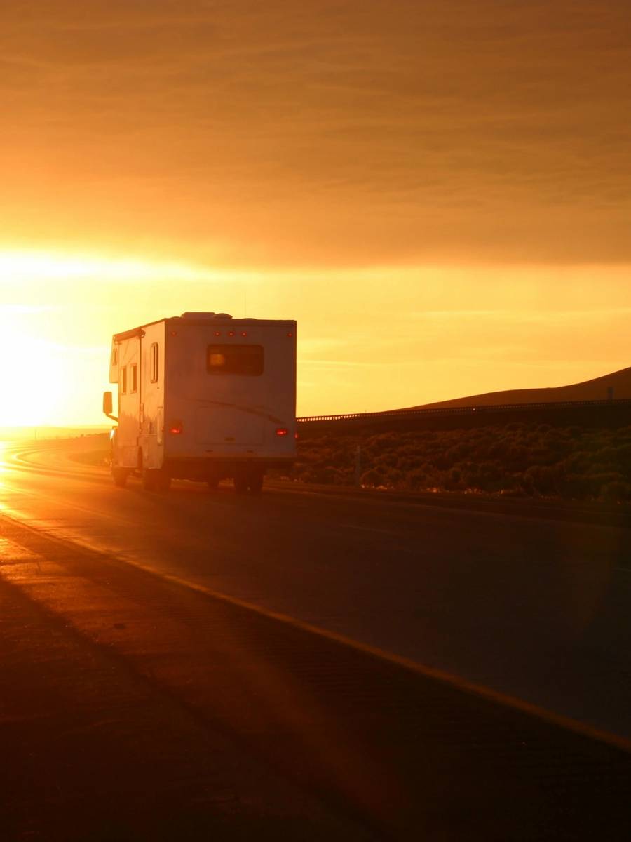 A white truck driving down the road at sunset.