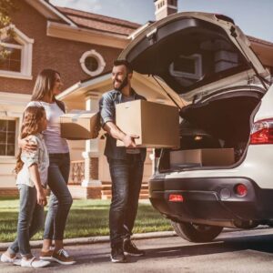 A family is loading boxes into the trunk of their car.