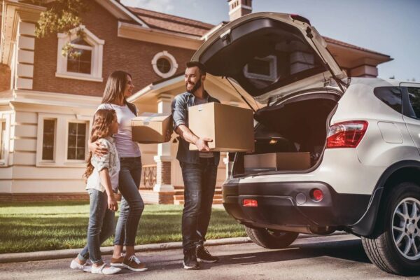 A family is loading boxes into the trunk of their car.