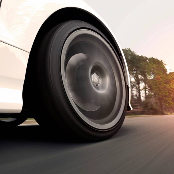 A car tire on the road with trees in background.