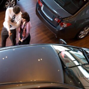 Two people standing in front of a car.