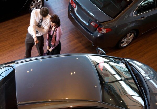 Two people standing in front of a car.