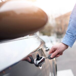 A person is holding the handle of their car.