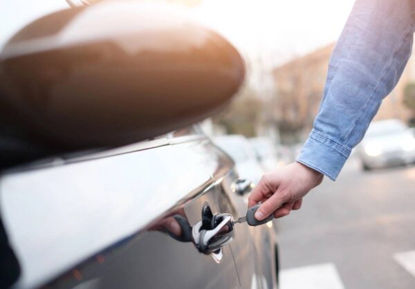 A person is holding the handle of their car.