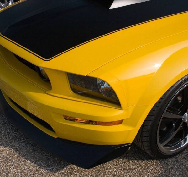 A close up of the front end of a yellow car