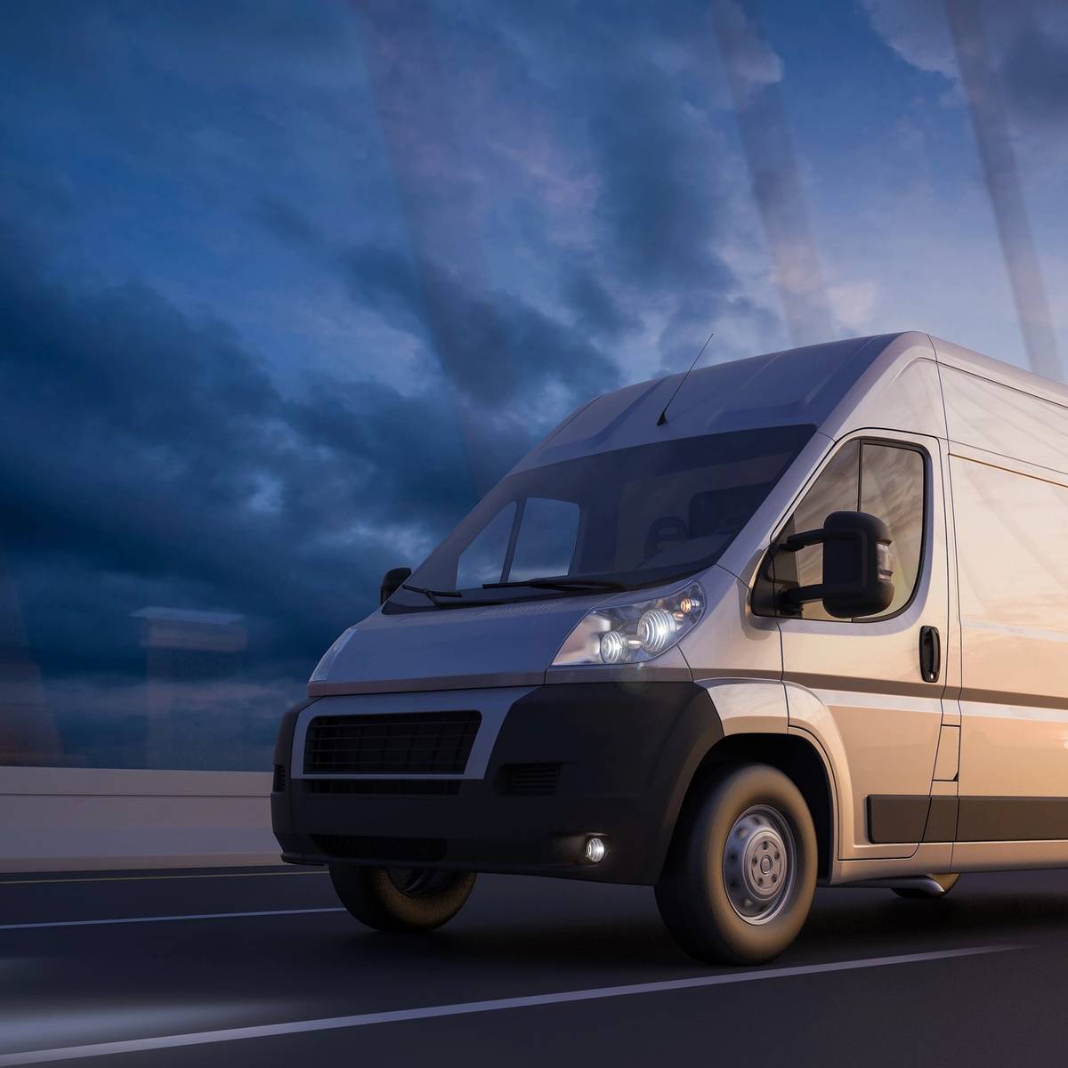 A van driving down the road under a cloudy sky.